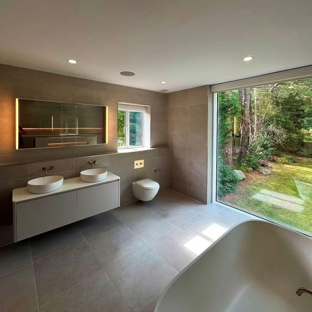 A large, modern bathroom with freestanding bathtub and a large window showing nature outside.