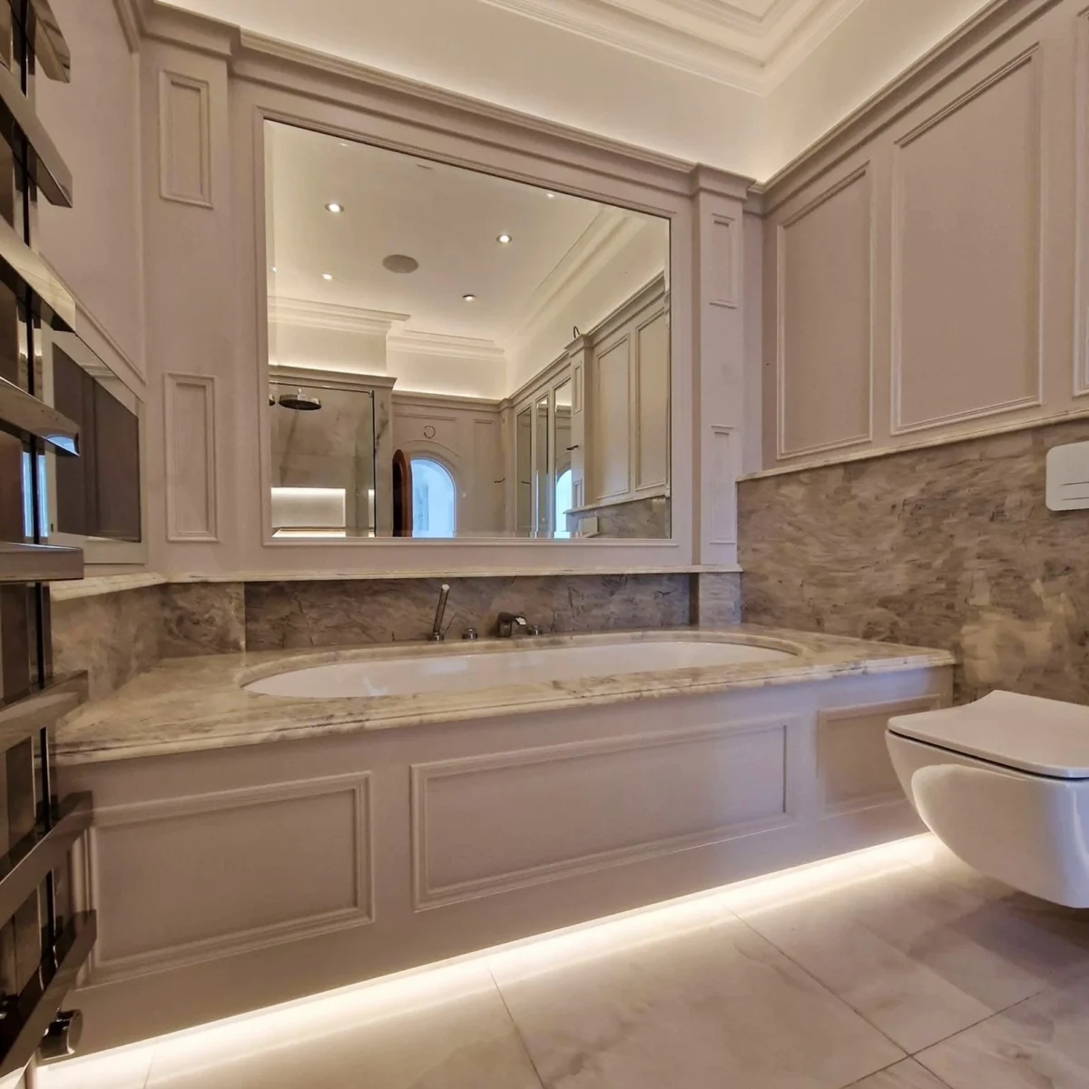 A traditional-style bathroom with a luxurious bath, large mirror, and wainscoting and panelling.
