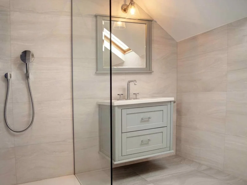 A minimalist bathroom with a large walk-in shower and a floating vanity unit in a light turquoise wood finish.