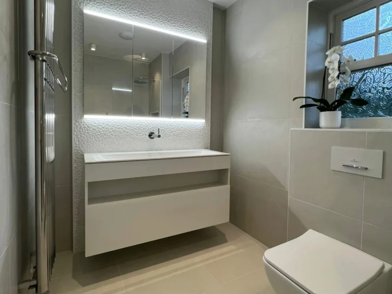 A spacious bathroom with marble-effect tiling, a freestanding bathtub, and a large floating vanity.