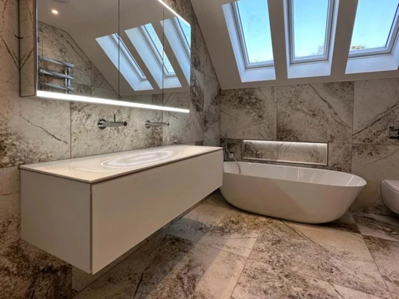 A minimalist bathroom featuring a white floating vanity, a backlit mirror against a textured wall, and a wall-hung toilet.