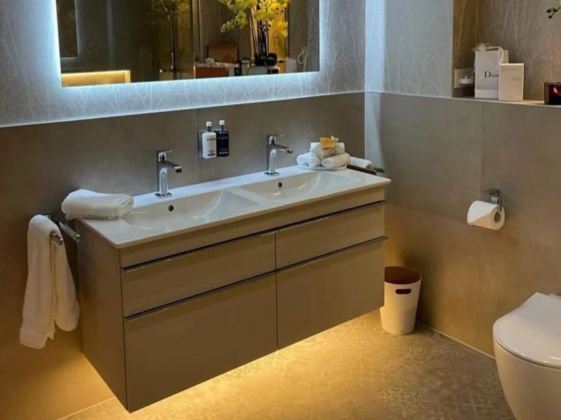 A modern bathroom with a large, backlit rectangular mirror above a floating vanity unit.