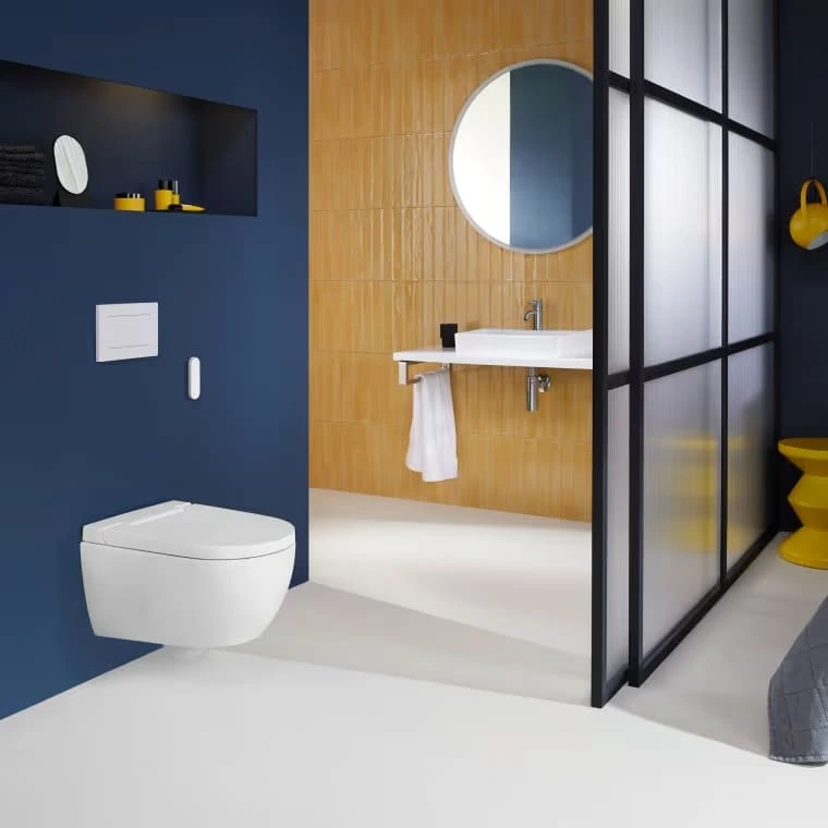 A modern bathroom with an integrated bidet toilet mounted to a navy-blue wall behind a sliding glass door.