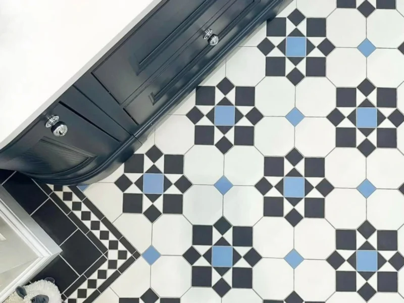 Mosaic-style bathroom tiles with a pattern of white, blue, and navy squares forming different shapes, with a black vanity unit above. 