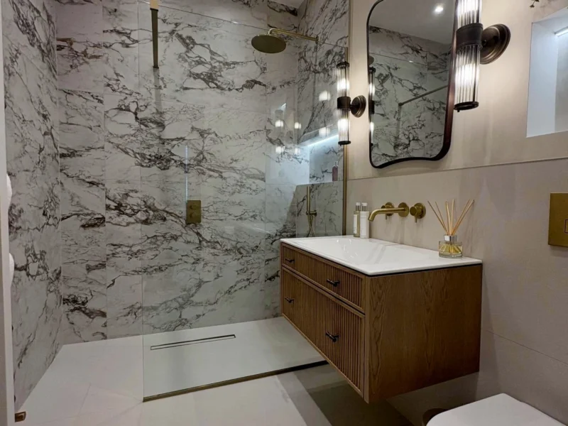 A floating vanity unit beneath a quirky mirror and wall-mounted sconces.