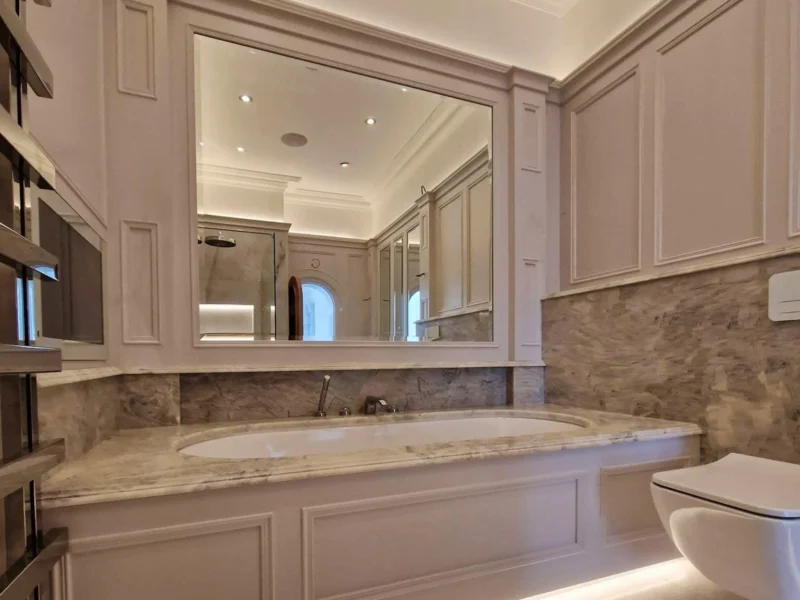A traditional-style bathroom with a luxurious bath, large mirror, and wainscoting and panelling.
